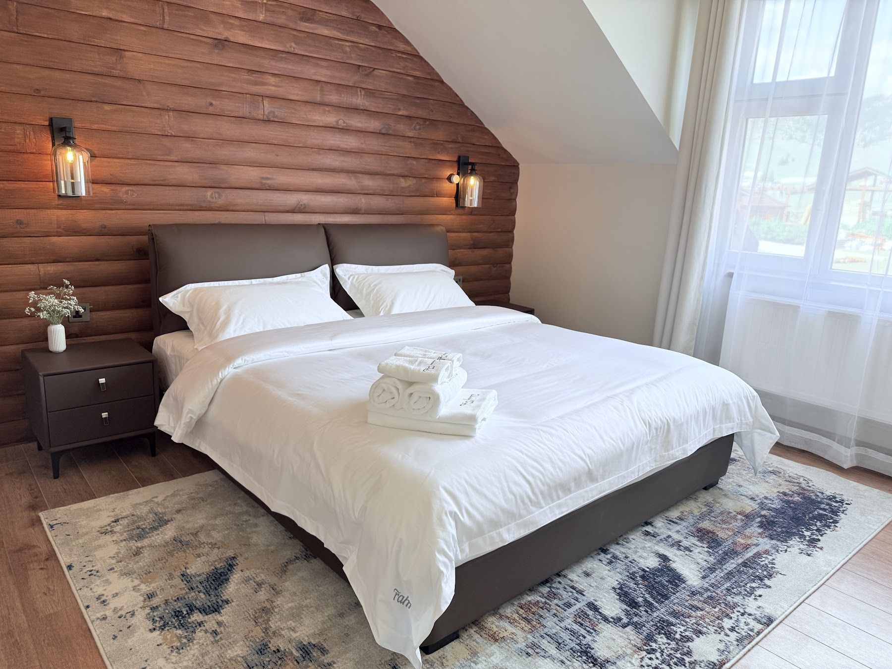 Lodge room with timber wall, king bed and iron chandelier